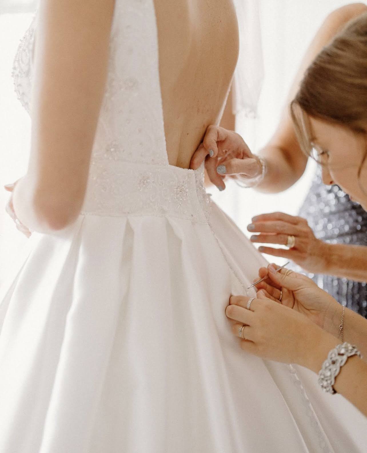 Bride having her wedding gown adjusted by her bridesmaid before the ceremony